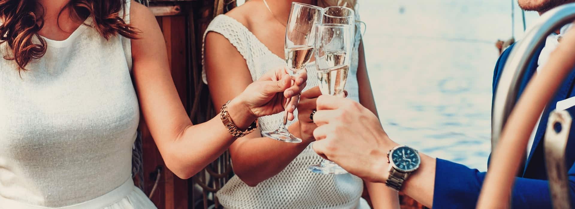 Friends raising champagne glasses together aboard a yacht.